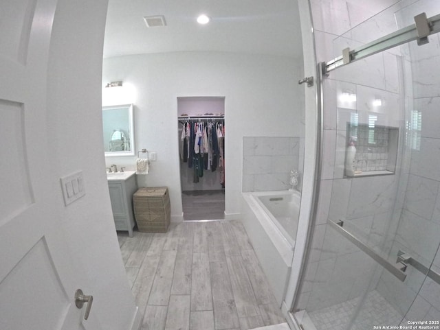 524 Flaman, Canyon Lake, TX 78133 - full bath featuring vanity, a bath, a shower stall, a walk in closet, and wood finished floors