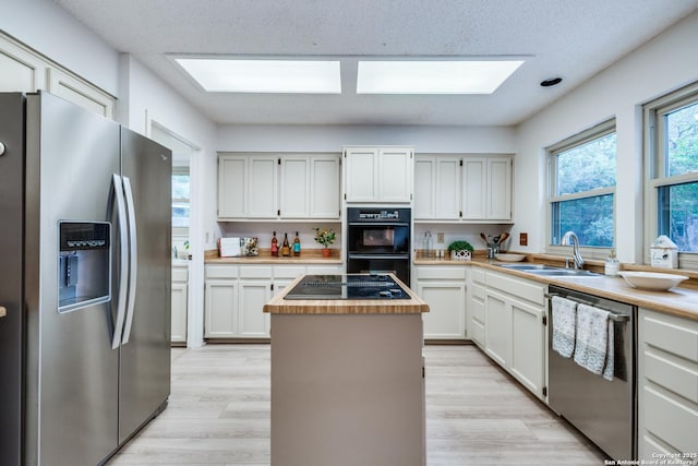 16930 Hidden Timber Wood, San Antonio, TX 78248 - kitchen featuring black appliances, wooden counters, a sink, a center island, and light wood finished floors