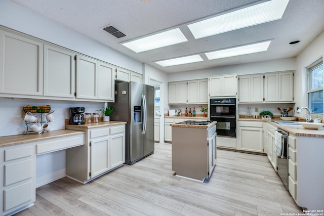 16930 Hidden Timber Wood, San Antonio, TX 78248 - kitchen featuring black appliances, a sink, light countertops, a center island, and light wood-type flooring