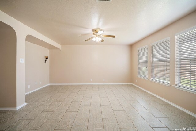 7731 Cedar Farm, San Antonio, TX 78239 - spare room with a ceiling fan, arched walkways, baseboards, and a textured ceiling