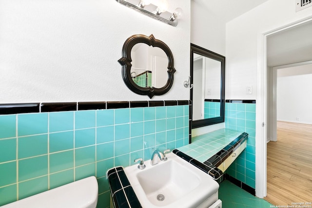 435 Sharon, San Antonio, TX 78216 - bathroom with tile walls, toilet, wainscoting, wood finished floors, and a sink