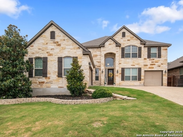 32337 Lavender Cv, Bulverde, TX 78163 - french country home featuring stone siding, a front yard, concrete driveway, and an attached garage