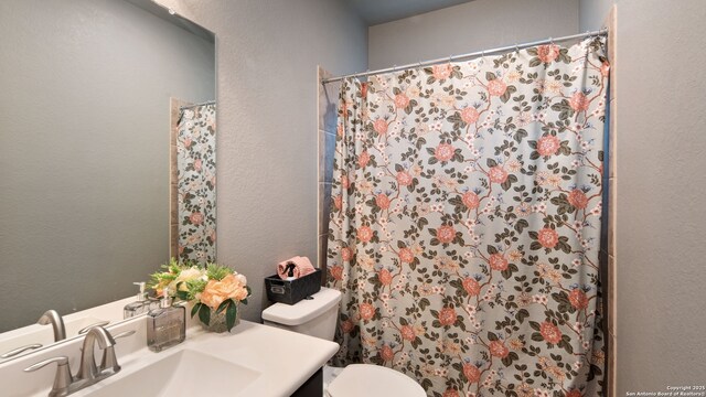32337 Lavender Cv, Bulverde, TX 78163 - full bathroom featuring toilet, vanity, curtained shower, and a textured wall