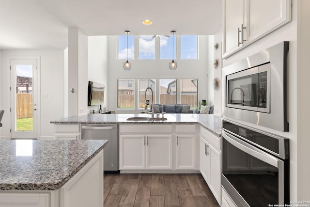 13917 Westbury Fls, San Antonio, TX 78253 - kitchen featuring appliances with stainless steel finishes, a sink, a peninsula, white cabinetry, and wood finished floors