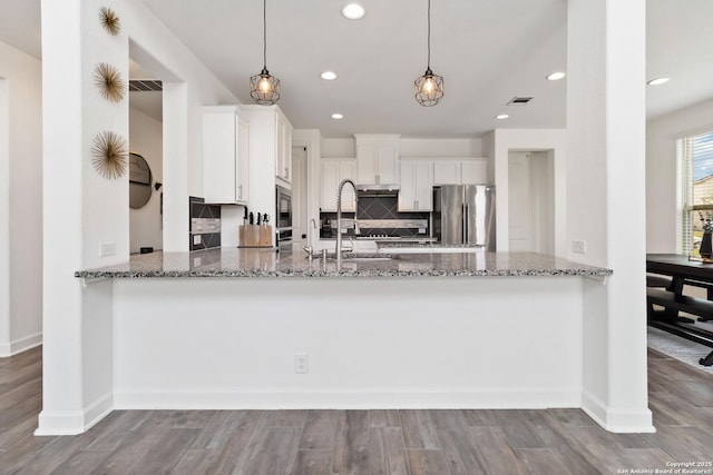 13917 Westbury Fls, San Antonio, TX 78253 - kitchen with freestanding refrigerator, a peninsula, light stone counters, backsplash, and white cabinets