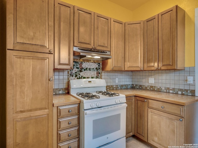 1211 W Magnolia Ave, San Antonio, TX 78201 - kitchen featuring white gas range oven, under cabinet range hood, tasteful backsplash, and tile counters