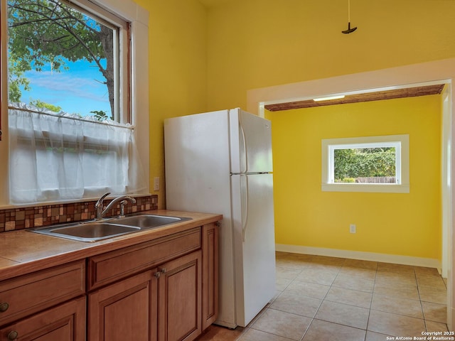 1211 W Magnolia Ave, San Antonio, TX 78201 - kitchen featuring a sink, freestanding refrigerator, brown cabinets, light tile patterned floors, and baseboards