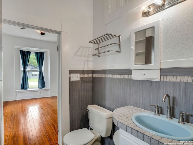 1211 W Magnolia Ave, San Antonio, TX 78201 - half bathroom with toilet, vanity, hardwood / wood-style floors, and a wainscoted wall