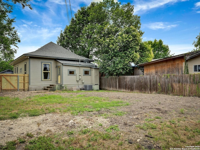 1211 W Magnolia Ave, San Antonio, TX 78201 - back of property with a fenced backyard, entry steps, central air condition unit, and a shingled roof