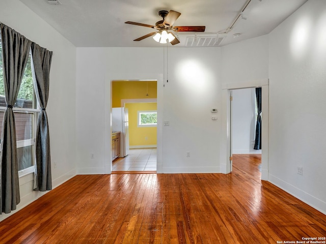 1211 W Magnolia Ave, San Antonio, TX 78201 - spare room featuring rail lighting, a ceiling fan, light wood-style floors, and baseboards
