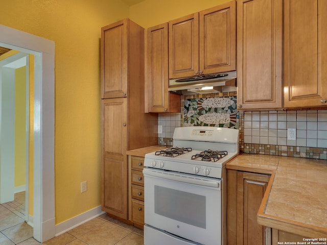 1211 W Magnolia Ave, San Antonio, TX 78201 - kitchen featuring white range with gas cooktop, under cabinet range hood, light countertops, and light tile patterned flooring