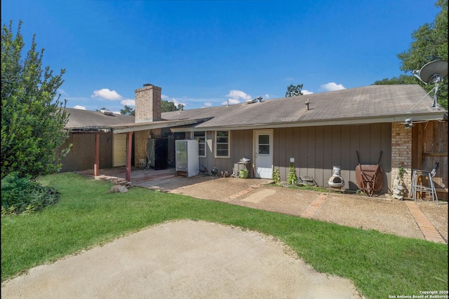 4911 Belle Ellen, San Antonio, TX 78229 - rear view of house featuring a chimney, a patio area, a lawn, and a shingled roof