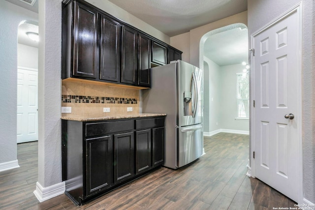 7030 Plains Way, San Antonio, TX 78253 - kitchen with arched walkways, stainless steel fridge, backsplash, dark wood-style flooring, and baseboards