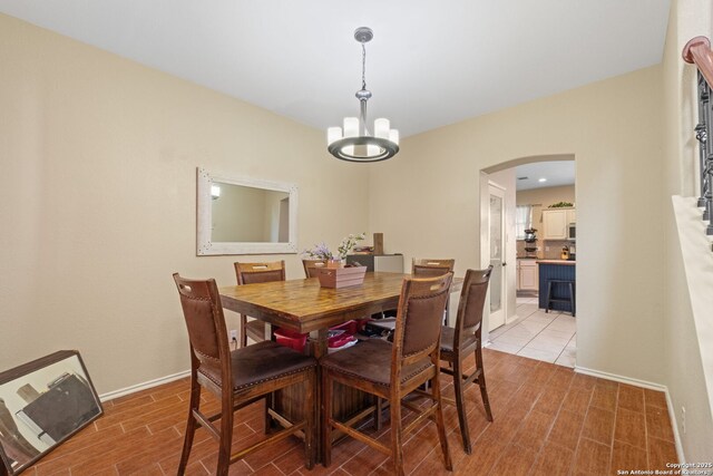 815 Maltese Gdn, San Antonio, TX 78260 - dining room featuring arched walkways, a chandelier, light wood-type flooring, and baseboards