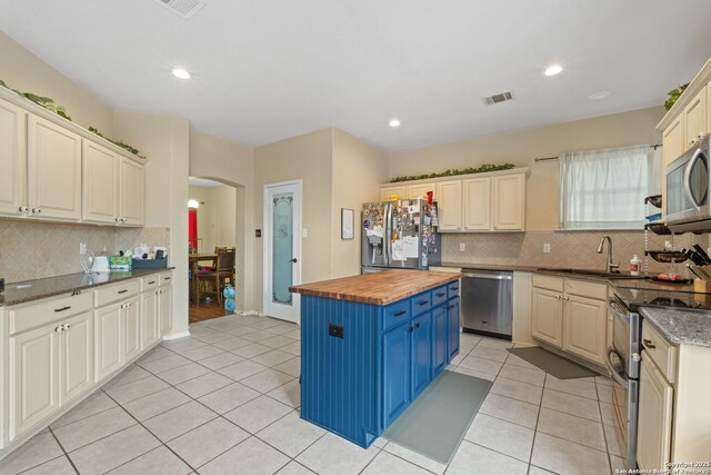 815 Maltese Gdn, San Antonio, TX 78260 - kitchen with appliances with stainless steel finishes, butcher block counters, blue cabinets, a sink, and decorative backsplash