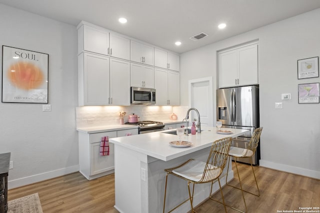 8851 Oakland Rd, San Antonio, TX 78240 - kitchen featuring stainless steel appliances, backsplash, white cabinets, light wood-type flooring, and recessed lighting