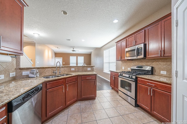 10736 Gemsbuck Ldg, San Antonio, TX 78245 - kitchen with appliances with stainless steel finishes, a sink, a peninsula, tasteful backsplash, and a textured ceiling