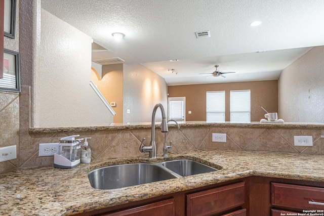 10736 Gemsbuck Ldg, San Antonio, TX 78245 - kitchen featuring a sink, decorative backsplash, a ceiling fan, light stone counters, and a textured wall