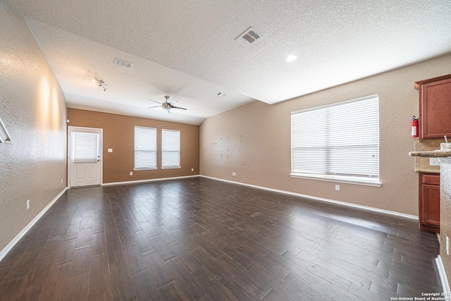 10736 Gemsbuck Ldg, San Antonio, TX 78245 - unfurnished living room featuring a textured ceiling, a ceiling fan, dark wood-style flooring, baseboards, and lofted ceiling