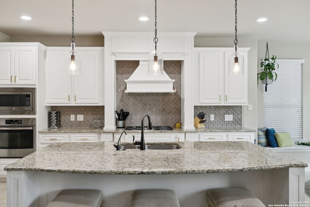 25723 Coreopsis, San Antonio, TX 78261 - kitchen featuring appliances with stainless steel finishes, custom range hood, a kitchen bar, recessed lighting, and white cabinetry