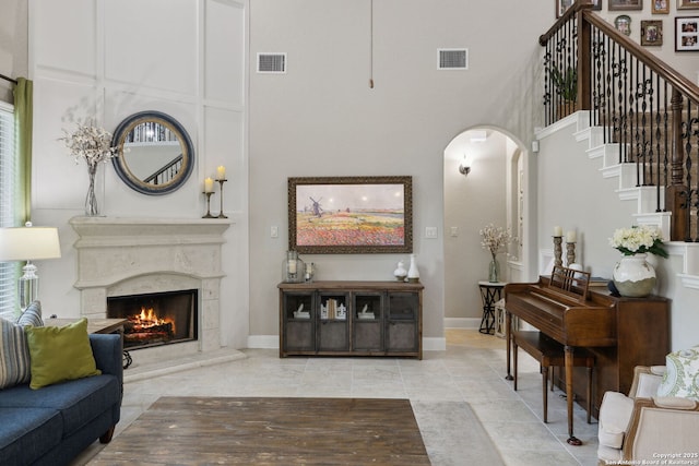 25723 Coreopsis, San Antonio, TX 78261 - living area with arched walkways, a high ceiling, a fireplace, stairway, and baseboards