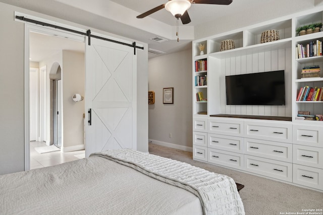 25723 Coreopsis, San Antonio, TX 78261 - bedroom with a barn door, light carpet, arched walkways, baseboards, and a ceiling fan