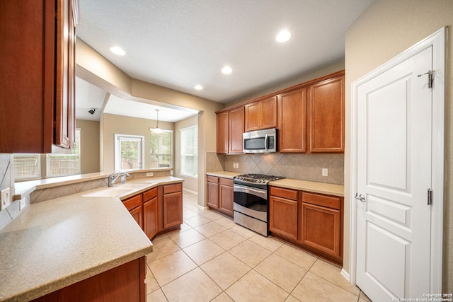 1014 Windy Pond, San Antonio, TX 78260 - kitchen featuring appliances with stainless steel finishes, a sink, decorative backsplash, a peninsula, and brown cabinetry