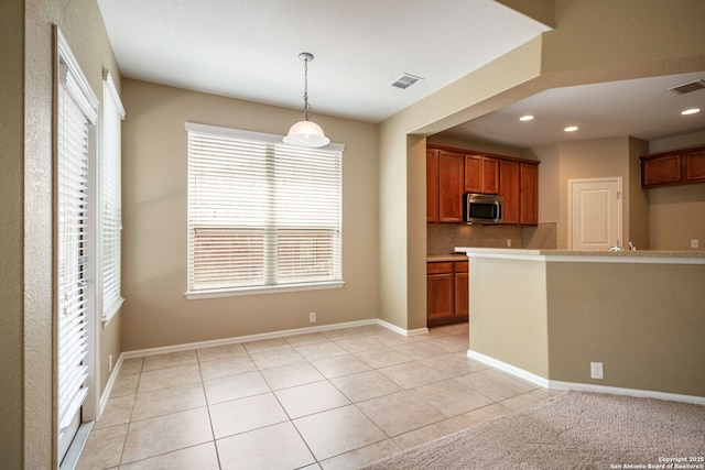 1014 Windy Pond, San Antonio, TX 78260 - kitchen featuring stainless steel microwave, hanging light fixtures, tasteful backsplash, brown cabinetry, and recessed lighting
