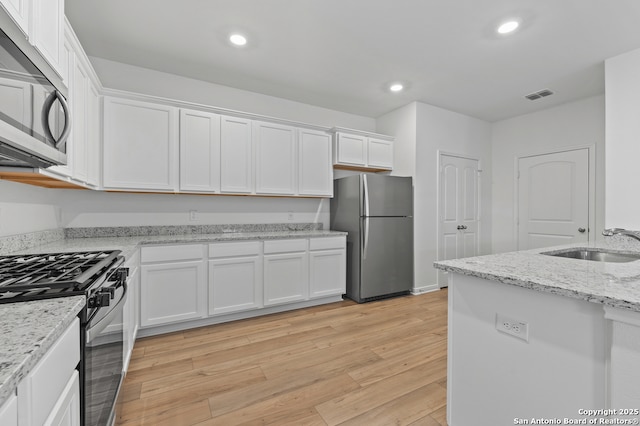 11502 Bald Eagle Hts, San Antonio, TX 78223 - kitchen featuring appliances with stainless steel finishes, a sink, white cabinetry, light wood-style floors, and recessed lighting