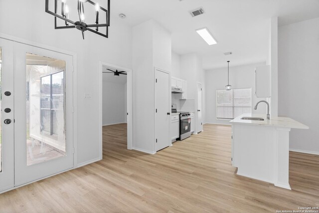 6610 Quail Lk, San Antonio, TX 78244 - kitchen with electric range, a sink, healthy amount of natural light, white cabinets, and high vaulted ceiling
