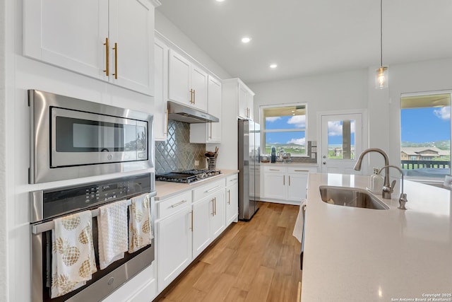 6827 Bella Verso, San Antonio, TX 78256 - kitchen featuring appliances with stainless steel finishes, a sink, light wood-style flooring, tasteful backsplash, and recessed lighting