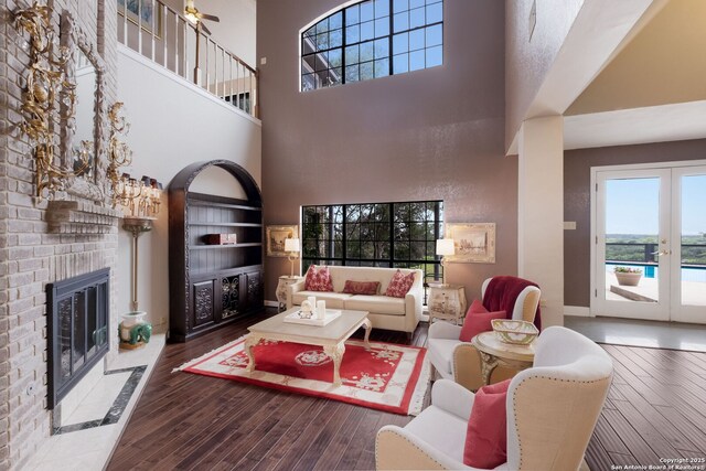 14706 War Admiral, San Antonio, TX 78248 - living room featuring wood finished floors, a fireplace, a towering ceiling, baseboards, and french doors