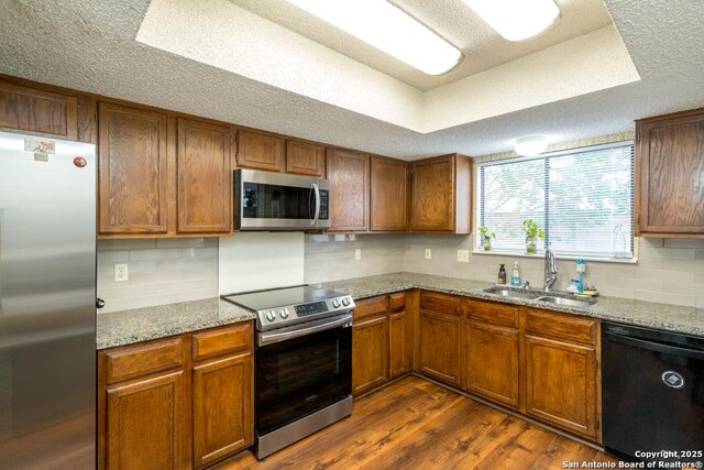 5823 Archwood, San Antonio, TX 78239 - kitchen featuring appliances with stainless steel finishes, a sink, dark wood-type flooring, tasteful backsplash, and a textured ceiling