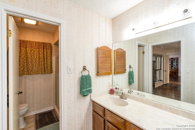 5823 Archwood, San Antonio, TX 78239 - bathroom with wallpapered walls, vanity, toilet, a shower stall, and a textured ceiling