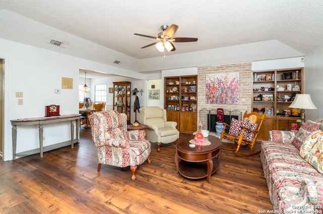 5823 Archwood, San Antonio, TX 78239 - living area featuring a ceiling fan, wood finished floors, a textured ceiling, a brick fireplace, and built in shelves