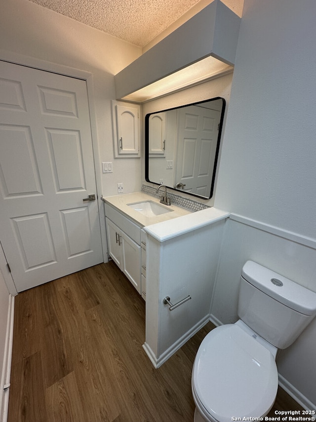 6127 Walking Gait, San Antonio, TX 78240 - bathroom featuring wood finished floors, vanity, a textured ceiling, toilet, and wainscoting