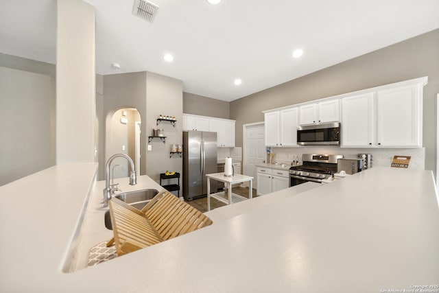 13014 Essen, Helotes, TX 78023 - kitchen featuring appliances with stainless steel finishes, arched walkways, backsplash, white cabinets, and a sink