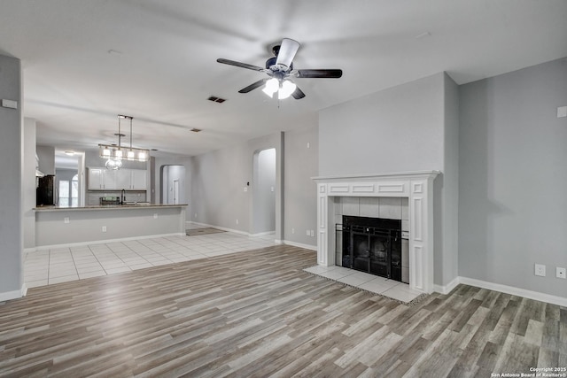 1947 Walter Raleigh, Windcrest, TX 78239 - unfurnished living room featuring light wood-style floors, ceiling fan, a fireplace, baseboards, and a sink