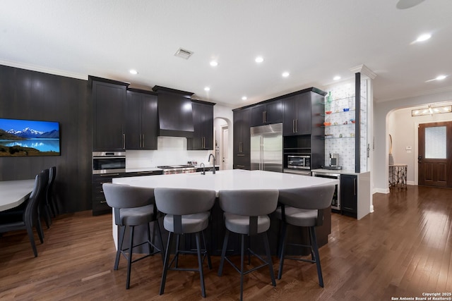 314 Regent Cir, Shavano Park, TX 78231 - kitchen featuring appliances with stainless steel finishes, crown molding, arched walkways, a kitchen island with sink, and open shelves