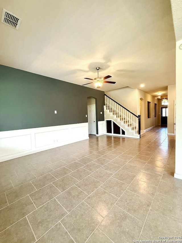 2035 Tillman Park, San Antonio, TX 78253 - tiled empty room featuring stairway, a ceiling fan, arched walkways, a decorative wall, and a wainscoted wall