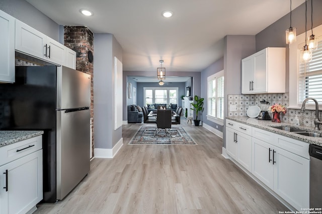 128 Blanco, San Antonio, TX 78212 - kitchen with a sink, appliances with stainless steel finishes, light stone countertops, white cabinets, and light wood-style floors