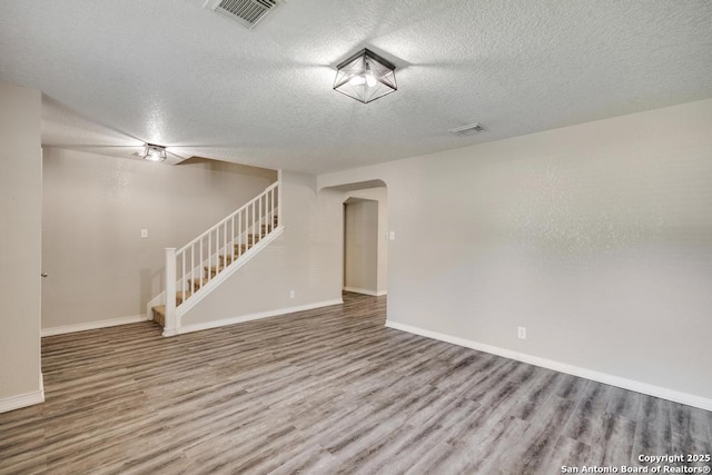 17214 Irongate Rail, San Antonio, TX 78247 - empty room with stairs, wood finished floors, a textured ceiling, arched walkways, and baseboards