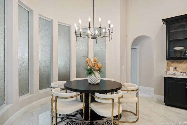3 Benchwood Cir, San Antonio, TX 78248 - dining space featuring light marble finish floors, arched walkways, a chandelier, and a towering ceiling