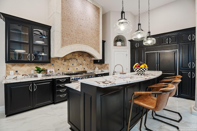 3 Benchwood Cir, San Antonio, TX 78248 - kitchen with light marble finish flooring, dark cabinets, a high ceiling, light stone counters, and a kitchen island with sink