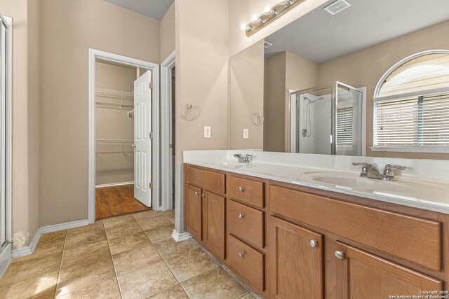 6218 Ozona Ml, San Antonio, TX 78253 - bathroom featuring a stall shower, double vanity, a walk in closet, and baseboards
