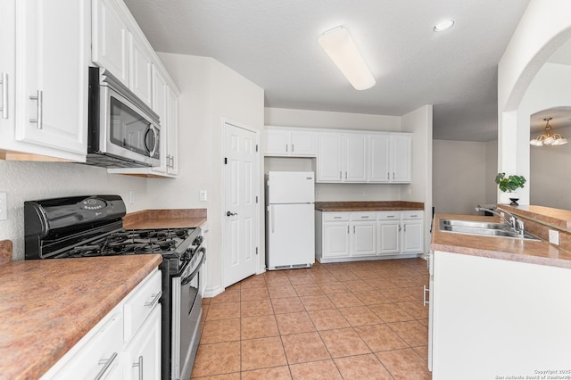 7619 Bit Cir, Elmendorf, TX 78112 - kitchen with range with gas cooktop, freestanding refrigerator, stainless steel microwave, a sink, and white cabinetry