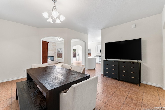 7619 Bit Cir, Elmendorf, TX 78112 - dining area featuring arched walkways, a chandelier, light tile patterned flooring, baseboards, and a fireplace