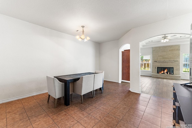 7619 Bit Cir, Elmendorf, TX 78112 - dining room with ceiling fan, a chandelier, arched walkways, a stone fireplace, and tile patterned floors