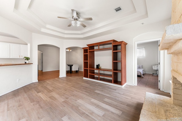 7619 Bit Cir, Elmendorf, TX 78112 - unfurnished living room with a tray ceiling, arched walkways, ceiling fan, and light wood finished floors