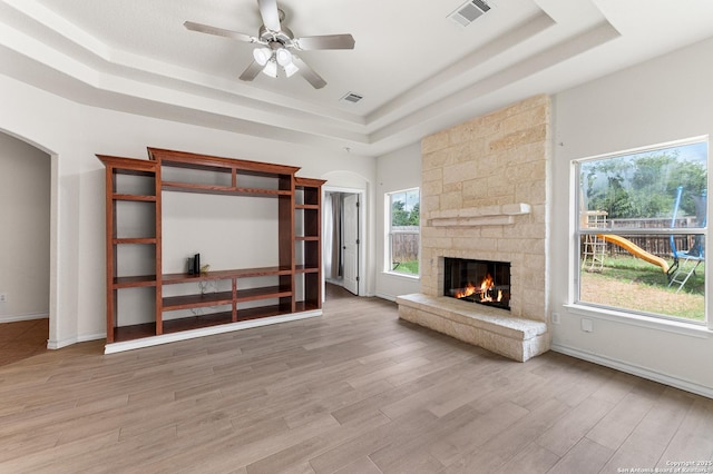 7619 Bit Cir, Elmendorf, TX 78112 - unfurnished living room with a raised ceiling, arched walkways, a fireplace, light wood-type flooring, and ceiling fan